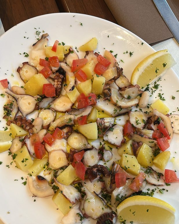 Octopus salad with potatoes, tomato and lemon