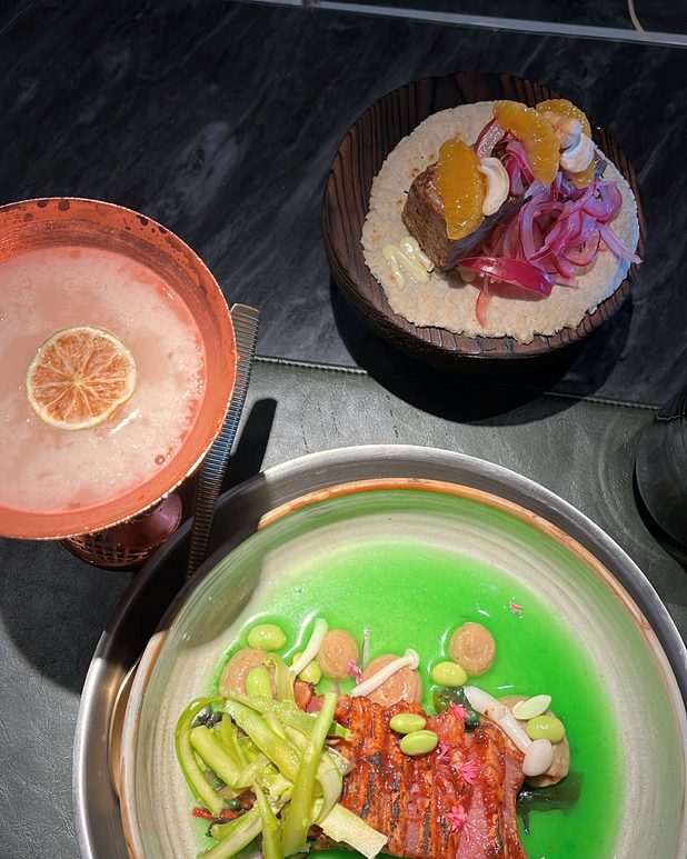 Trout over a vivid green sauce, with a cocktail alongside